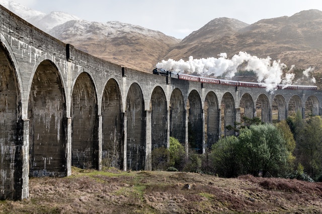 parní vlak s kouřícím komínem jede po mostě
