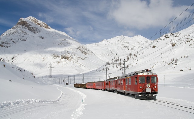 červená lokomotiva jede po kolejích v zimě na horách